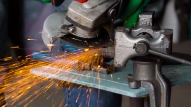 Köşeli taşlama tezgahı ile erkek işçi metal kesme işlemi. Ağır çekim