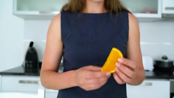 Mujer cortando y comiendo naranja en una cocina moderna — Vídeo de stock