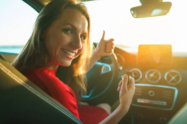 Mujer feliz en un vestido rojo con una llave en la mano está sentado en — Foto de Stock