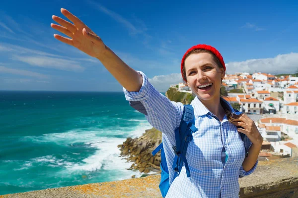 Donna con uno zaino fa un gesto di benvenuto mano sull'oceano — Foto Stock