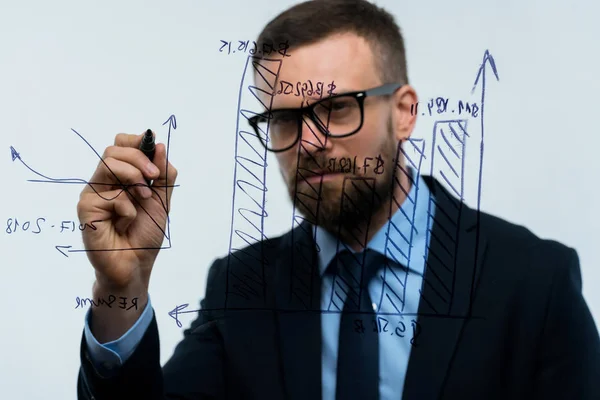 El hombre dibuja varios gráficos de crecimiento, calculando las perspectivas de éxito —  Fotos de Stock