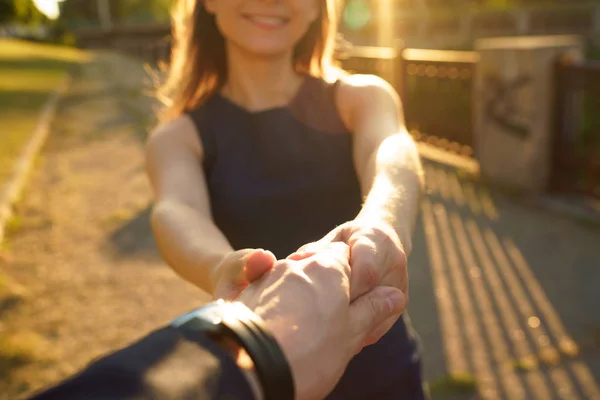 Volg mij - gelukkige jonge vrouw trekken guy's hand - hand in hand — Stockfoto