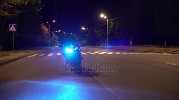 Nie do poznania rowerzysta jedzie na motocyklu na drodze pośród drzew w nocy — Wideo stockowe
