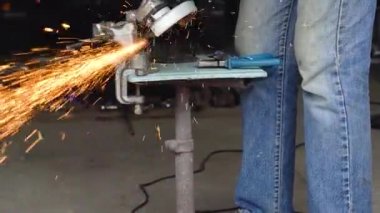 Köşeli taşlama tezgahı ile erkek işçi metal kesme işlemi. Ağır çekim