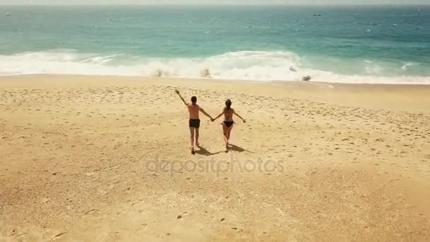 Счастливая пара беззаботно бежит к воде на пляже. Живописное побережье Португалии — стоковое видео