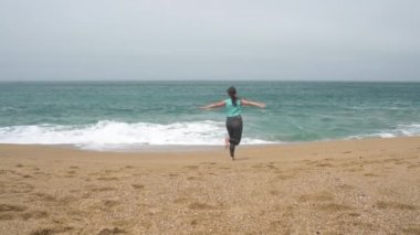 Mutlu kız plaj boyunca ileri geri çalışır. Portekiz Atlas Okyanusu'nda ıssız kıyısında. Ağır çekim