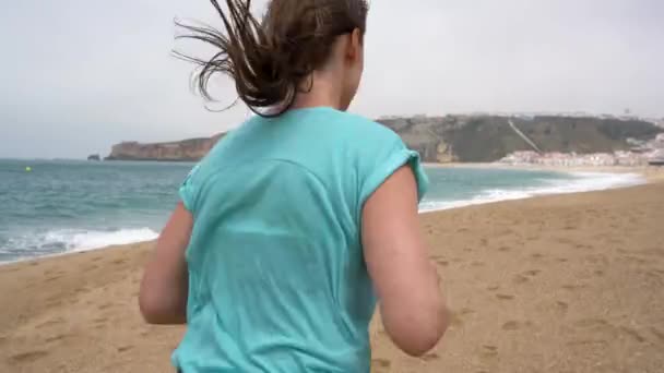 Kobieta lekkoatletycznego biegnącej wzdłuż plaży — Wideo stockowe