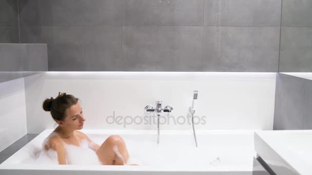 La mujer se relaja y toma un baño con espuma — Vídeo de stock