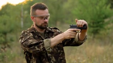 Genç adam bir silahtan ateş kamuflaj yakın çekim