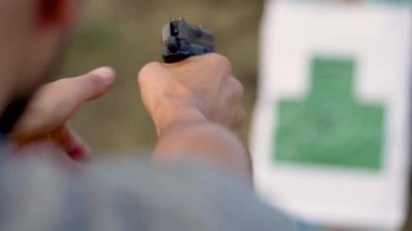 Genç adam bir silahtan hedefe ateş ediyor, yakın çekim