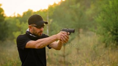 Genç adam bir silahtan ateş kamuflaj kapatın. Ağır çekim