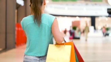 Bir alışveriş merkezinde bir smartphone cep telefonu ile konuşurken kağıt poşet olan kadın