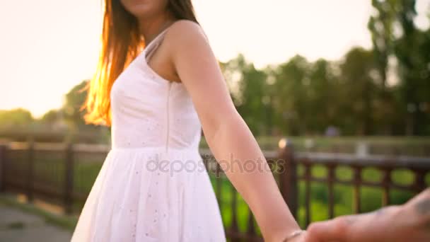 Follow me - girl leads the guy by the hand along the street at sunset — Stock Video