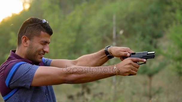 Young arab man is shooting from a gun, close up. Slow motion — Stock Video