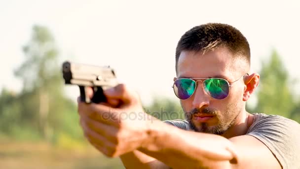 Молодой человек с пистолетом собирается выстрелить крупным планом — стоковое видео