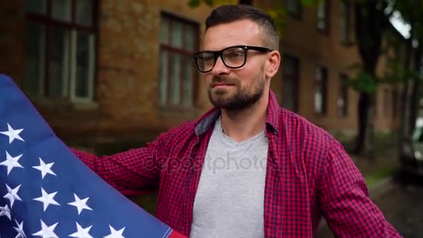 Mann schwenkt US-Flagge, während er die Straße entlangläuft - das Konzept des Unabhängigkeitstages — Stockvideo