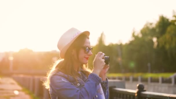 Chica está caminando por la ciudad y tomar fotos de la naturaleza y las vistas en una cámara de cine — Vídeo de stock