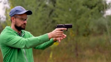 Genç adam bir silahtan ateş ediyor, yakın çekim