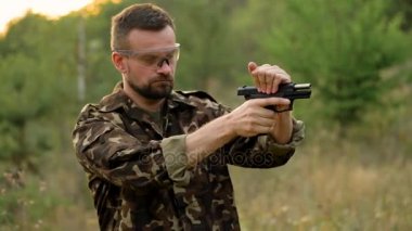 Genç adam bir silahtan ateş kamuflaj kapatın. Ağır çekim