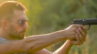 Genç adam bir silahtan ateş ediyor, yakın çekim. Egzersiz çekim