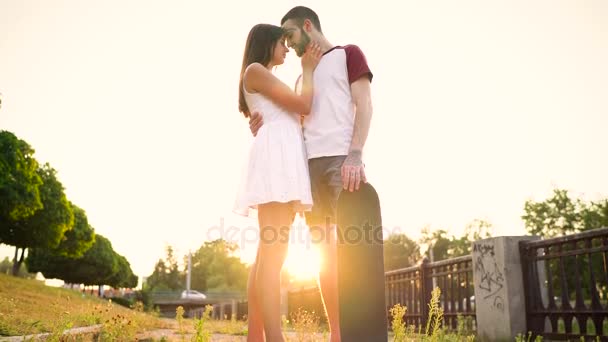 Молодая пара влюблённая целуется на улице на закате — стоковое видео