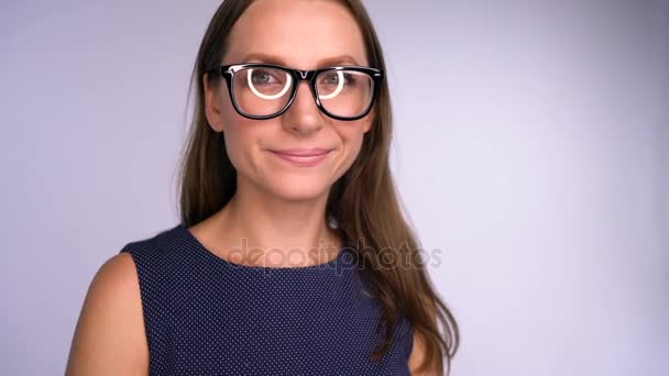 Joven mujer de negocios en gafas mirando a la cámara feliz. Deslumbramiento redondo se refleja en las gafas — Vídeos de Stock