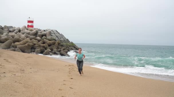 Mujer atlética corriendo por la playa. Movimiento lento — Vídeos de Stock