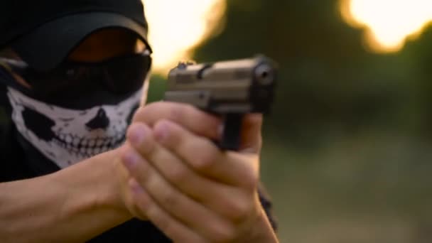 Man with the face closed with a handkerchief and sunglasses getting ready to shoot a gun, close up — Stock Video