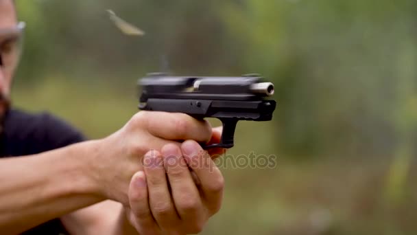 Молодой человек стреляет из пистолета, крупным планом. Медленное движение — стоковое видео