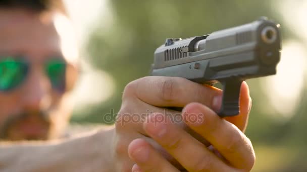 El joven está disparando con un arma, de cerca. Movimiento lento — Vídeo de stock