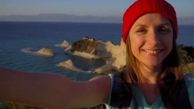 Kadın bir sırt çantası ile Yunanistan Corfu Island Cape Drastis arka plan üzerinde selfie yapar