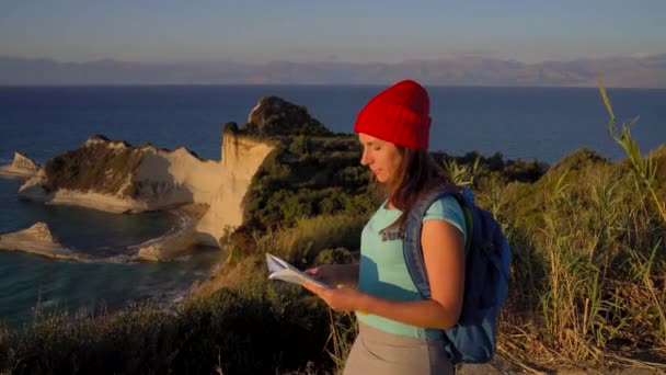 Una mujer con una mochila y un mapa va al cabo Drastis en la isla de Corfú en Grecia — Vídeos de Stock