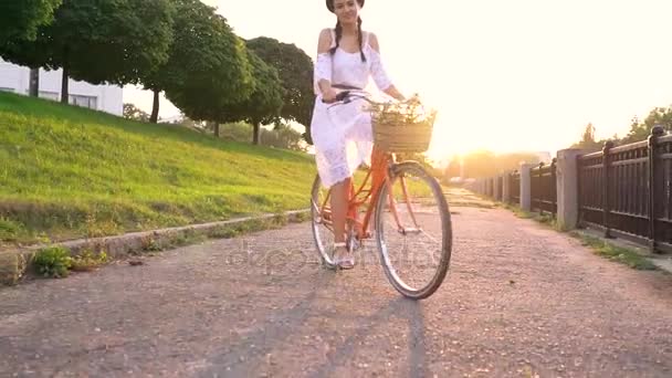 Mooie jongedame fietsen bij zonsondergang. Video genomen op verschillende snelheden — Stockvideo