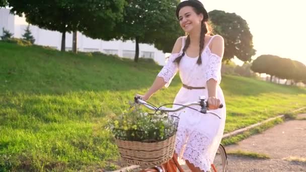 Mulher bonita nova que monta uma bicicleta no por do sol. Movimento lento — Vídeo de Stock