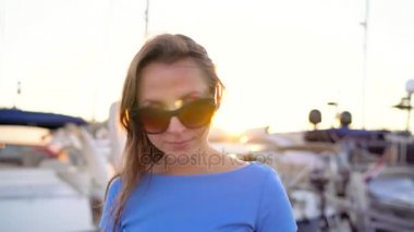Kadın güneş gözlüğü smartphone üzerinde söz ederken yürüyen bir dock yat ve tekne batımında yakın bir sürü ile aşağı yukarı, yakın çekim