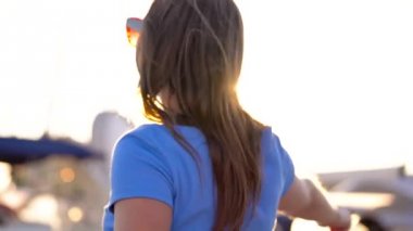 Gün batımında, yat ve tekne bir sürü rıhtım boyunca yürüyüş güneş gözlüğü kadında kapatın. Ağır çekim