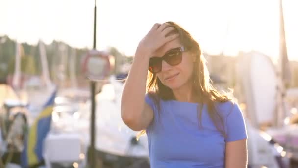 Femme en lunettes de soleil marchant le long du quai avec beaucoup de yachts et bateaux au coucher du soleil, gros plan — Video