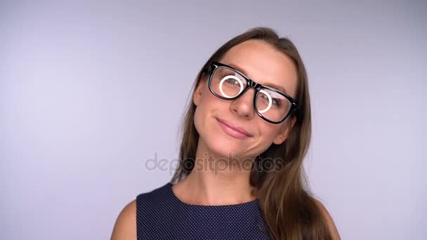 Joven mujer de negocios en gafas mirando a la cámara feliz. Deslumbramiento redondo se refleja en las gafas — Vídeos de Stock