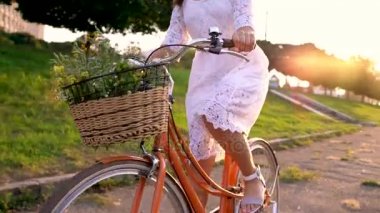 Genç güzel kadın günbatımında bir bisiklet sürme. Ağır çekim