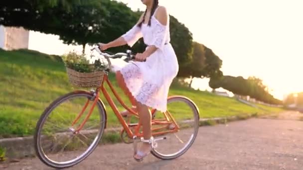 Młoda kobieta piękna, jazda na rowerze o zachodzie słońca. Film wideo przy różnych prędkościach — Wideo stockowe