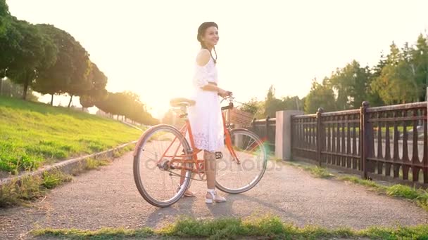Junge schöne Frau auf einem Fahrrad bei Sonnenuntergang. Zeitlupe — Stockvideo