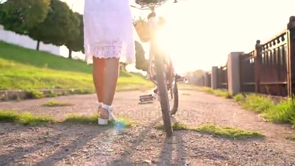 Mladá krásná žena chůze se kolo při západu slunce. Zpomalený pohyb