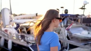 Gün batımında, yat ve tekne bir sürü rıhtım boyunca yürüyüş güneş gözlüklü kadın yakın çekim