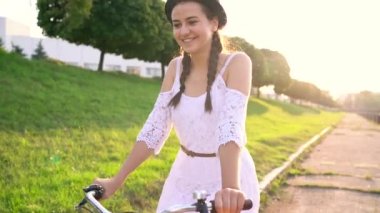 Genç güzel kadın günbatımında bir bisiklet sürme. Ağır çekim