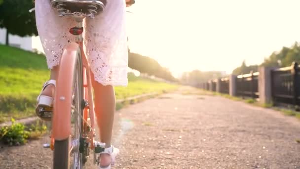 Mulher bonita nova que monta uma bicicleta no por do sol. Movimento lento — Vídeo de Stock