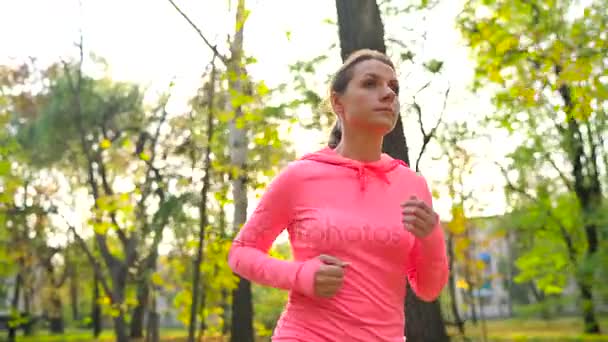 Közelről nő fut át az őszi park, naplementekor. Lassú mozgás — Stock videók