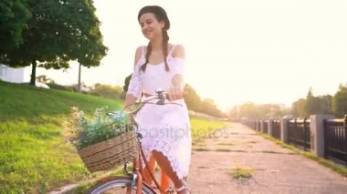 Günbatımında bir bisiklet sürme genç güzel kadın