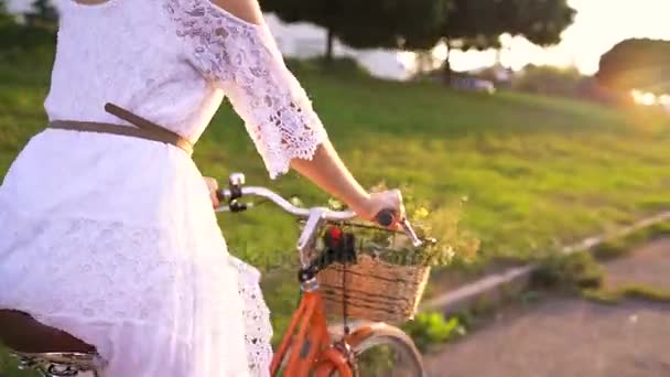 Joven hermosa mujer montando una bicicleta al atardecer — Vídeo de stock