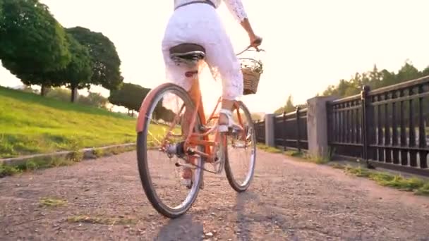 Mulher bonita nova que está perto de sua bicicleta no por do sol. Movimento lento — Vídeo de Stock