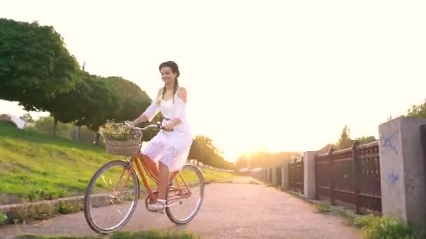 Ung vacker kvinna som rider en cykel vid solnedgången — Stockvideo